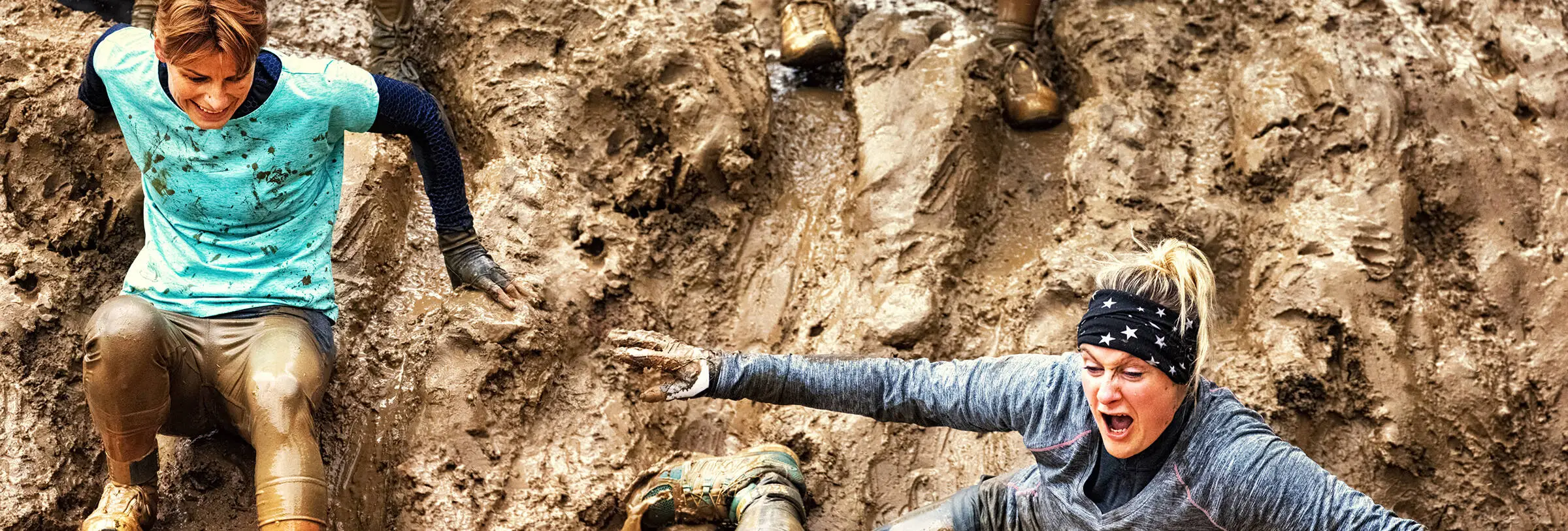 Muddy Angel Run in München - Ladies' Business Club Zwei Frauen im Sportoutfit sind im Schlamm.