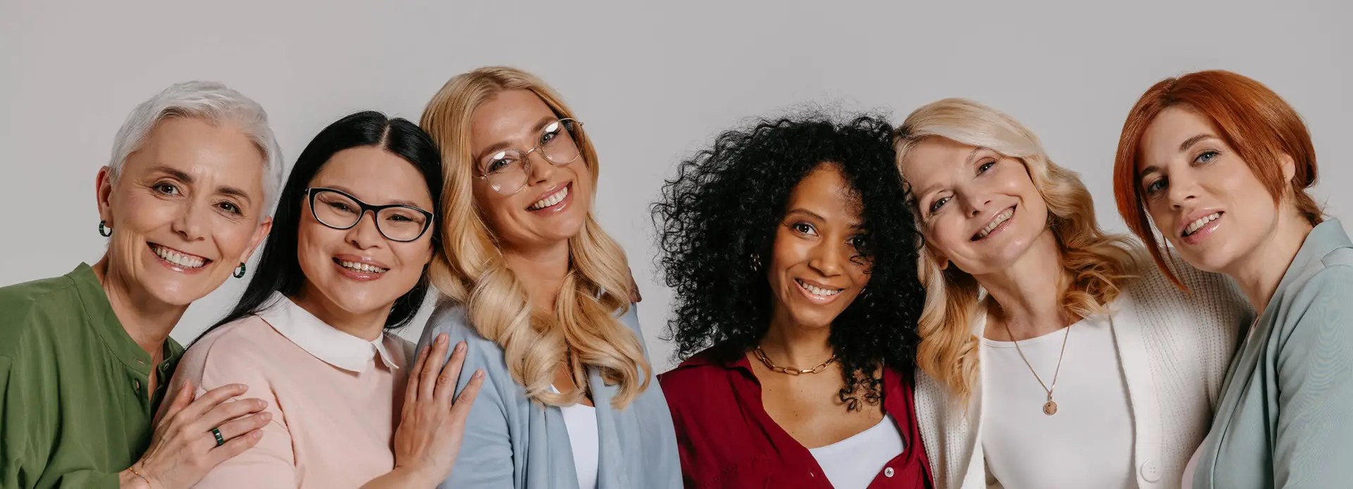 Multiethnische Frauengruppe schaut in die Kamera und lächelt.
