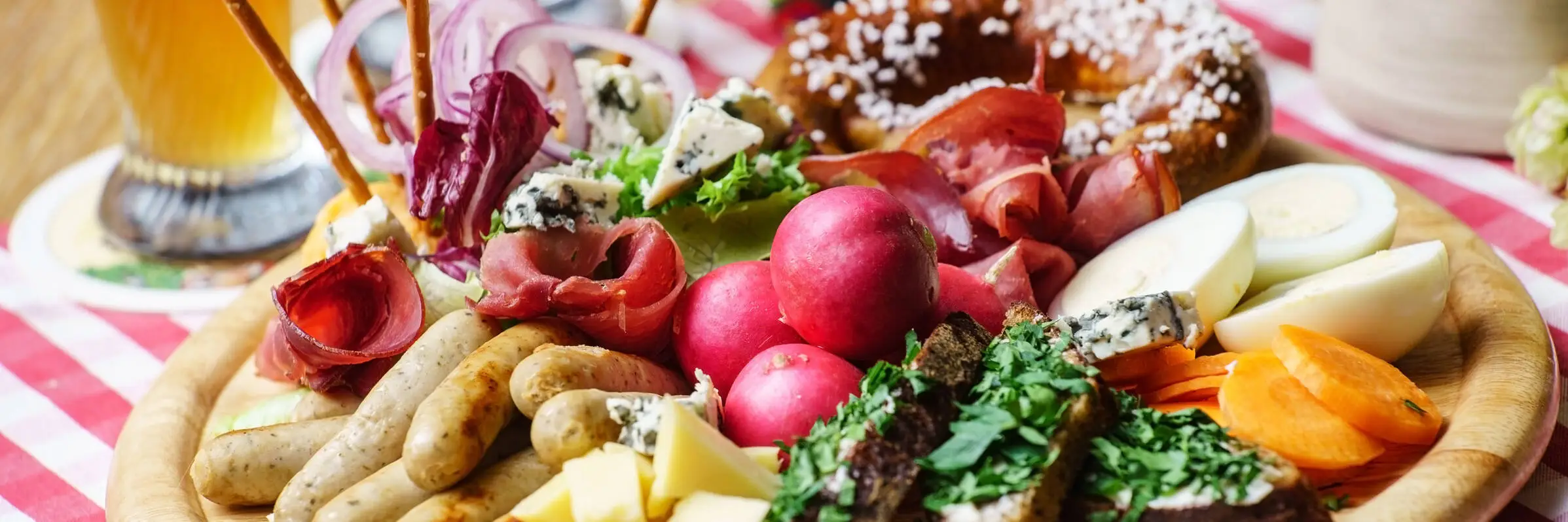 Wiesn Business Lunch in München - Ladies' Business Club Nahaufnahme von einem Oktoberfestteller mit Bratwurst, Brot, Schinken und Gemüse.