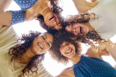 Ladies Business Special Events Vier Frauen schauen im Krais nach unten und lachen.